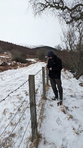 Seth Howell reattaching songbird feeder brackets in the snow